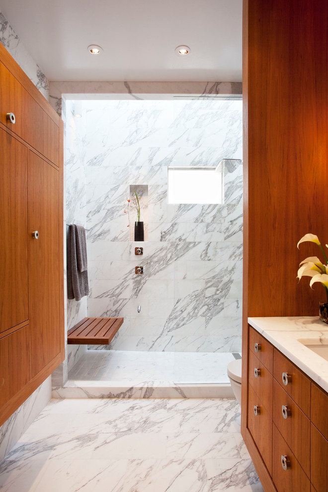Свежая идея для дизайна: ванная комната в современном стиле с врезной раковиной, плоскими фасадами, фасадами цвета дерева среднего тона, душем в нише и белой плиткой - отличное фото интерьера