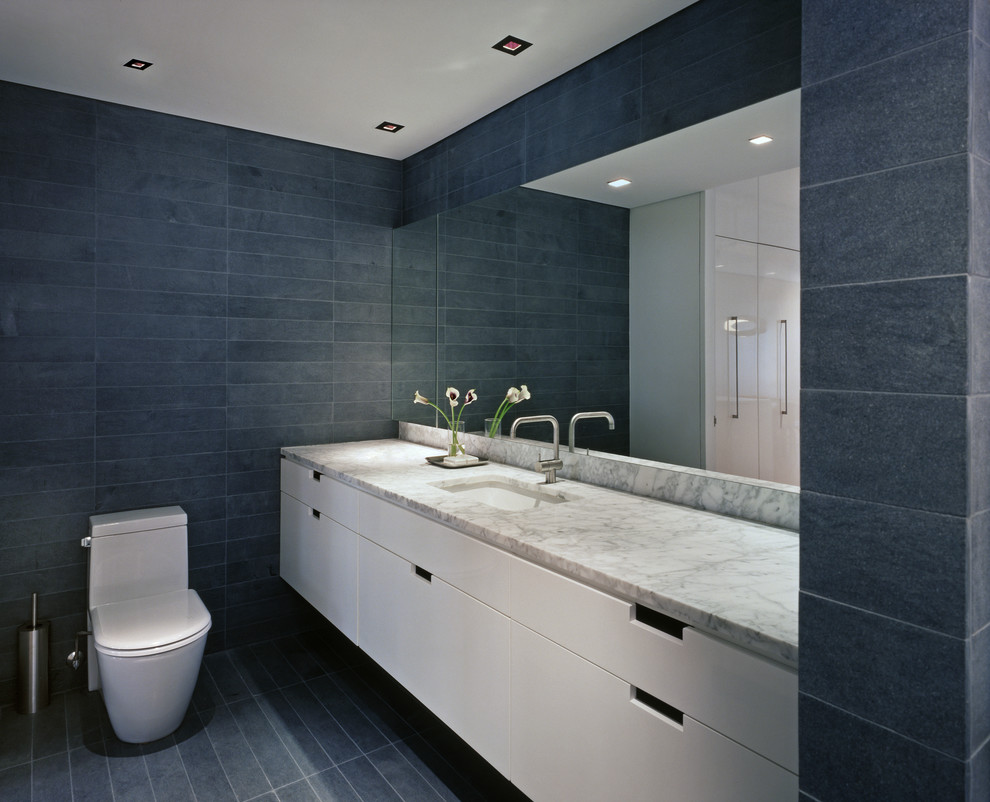 Inspiration pour une salle de bain grise et blanche design avec un lavabo encastré, un placard à porte plane, des portes de placard blanches, WC à poser et un carrelage gris.