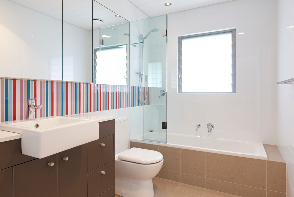 Cette photo montre une salle de bain tendance avec un placard à porte plane, des portes de placard marrons, une baignoire en alcôve, un combiné douche/baignoire, un carrelage multicolore et un mur blanc.
