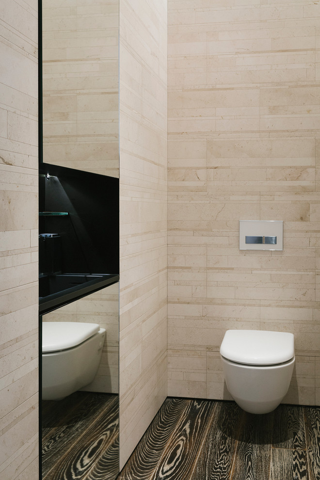 Modelo de cuarto de baño principal actual con sanitario de pared, baldosas y/o azulejos beige, suelo de madera oscura, baldosas y/o azulejos de piedra, paredes marrones y lavabo sobreencimera