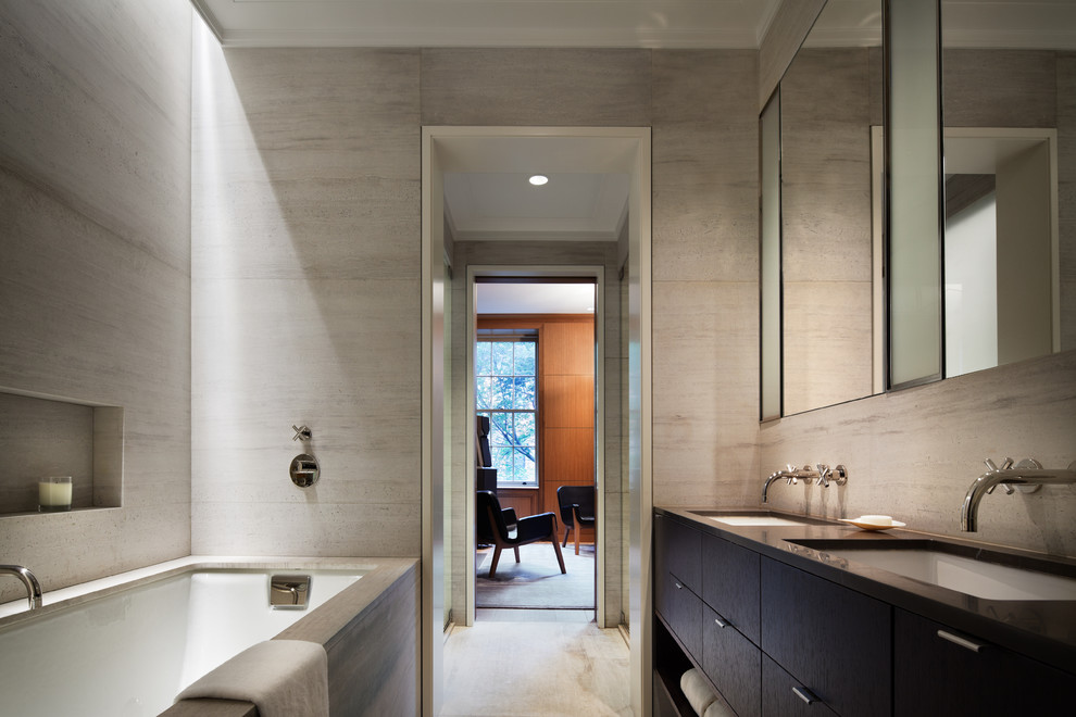 Inspiration for a modern grey and black ensuite bathroom in New York with flat-panel cabinets, brown cabinets, an alcove bath, grey tiles, grey walls, a submerged sink and beige floors.