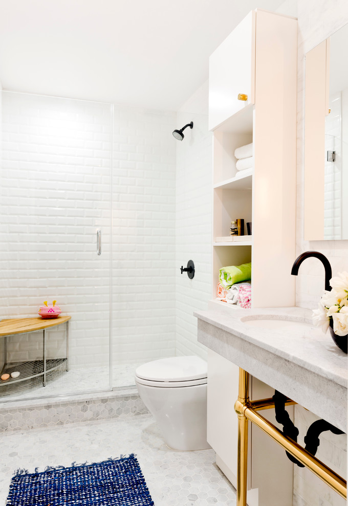 ニューヨークにある中くらいなトランジショナルスタイルのおしゃれなバスルーム (浴槽なし) (オープンシェルフ、白いキャビネット、アルコーブ型シャワー、白いタイル、サブウェイタイル、白い壁、モザイクタイル、アンダーカウンター洗面器、一体型トイレ	、大理石の洗面台) の写真
