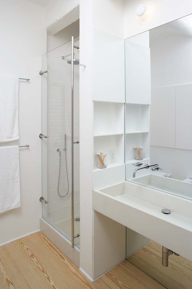 Bild på ett funkis badrum, med öppna hyllor, vita skåp, en dusch i en alkov, en vägghängd toalettstol, vit kakel, keramikplattor och ett avlångt handfat