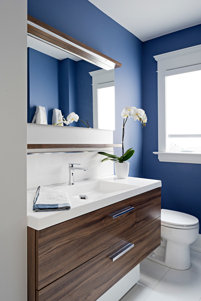 Design ideas for a small contemporary family bathroom in Toronto with flat-panel cabinets, dark wood cabinets, blue walls, ceramic flooring, an integrated sink, solid surface worktops, grey floors and white worktops.