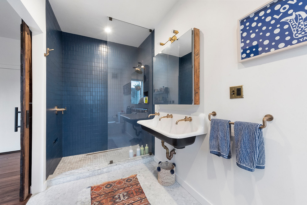 Inredning av ett modernt badrum, med en dusch i en alkov, blå kakel, vita väggar, ett fristående handfat, vitt golv och med dusch som är öppen