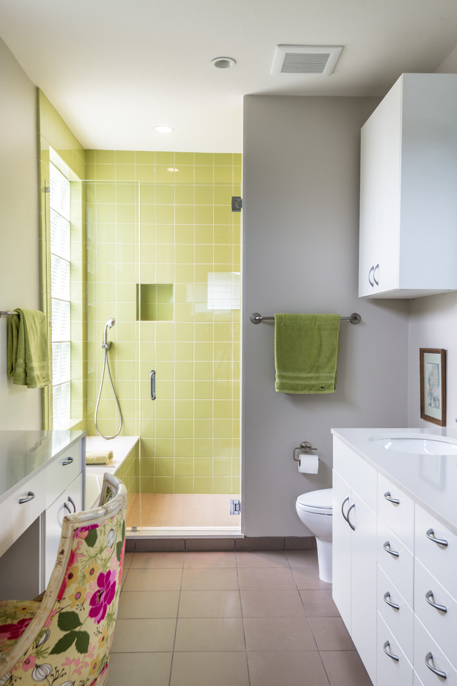 Modern inredning av ett en-suite badrum, med släta luckor, bänkskiva i kvartsit, ett undermonterad handfat, vita skåp, en dusch i en alkov, grön kakel, grå väggar och beiget golv