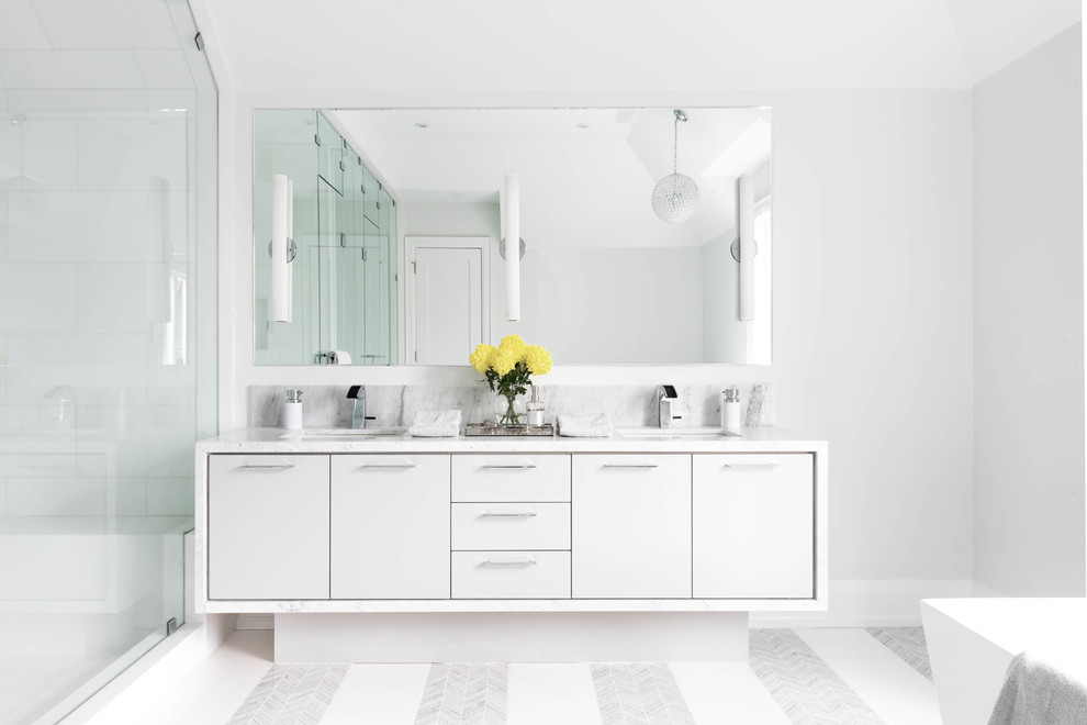Cette photo montre une grande salle de bain principale tendance avec un placard à porte plane, un carrelage blanc, un mur blanc, un sol en marbre, un lavabo encastré, un plan de toilette en marbre et des portes de placard blanches.
