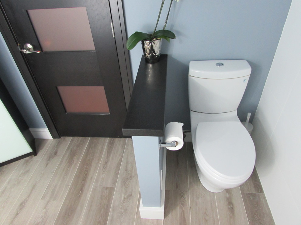 Example of a small trendy master blue tile and ceramic tile medium tone wood floor corner shower design in Portland with tile countertops, a one-piece toilet, blue walls, flat-panel cabinets and an integrated sink