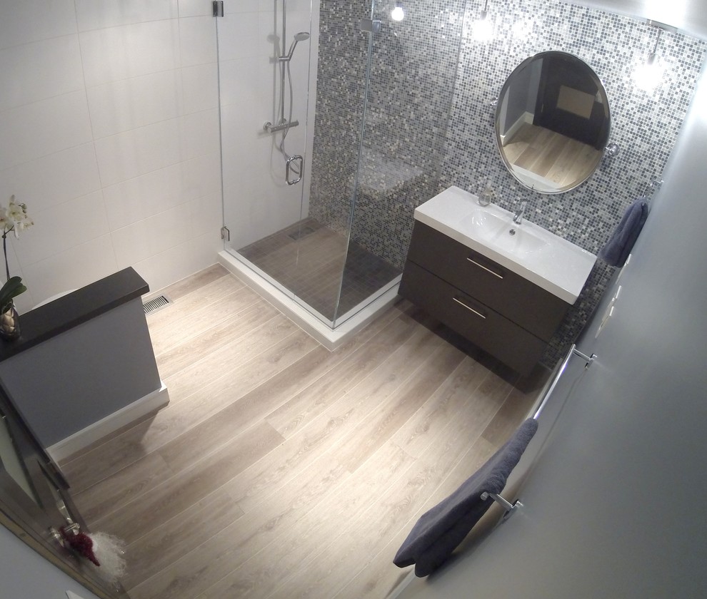ポートランドにある高級な小さなコンテンポラリースタイルのおしゃれなマスターバスルーム (コーナー設置型シャワー、一体型トイレ	、青いタイル、白い壁、無垢フローリング、一体型シンク、フラットパネル扉のキャビネット) の写真