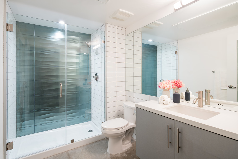 Diseño de cuarto de baño actual, de tamaño medio, con armarios con paneles lisos, sanitario de una pieza, baldosas y/o azulejos de cemento, paredes blancas, suelo de cemento, lavabo bajoencimera, encimera de cuarzo compacto, encimeras blancas, puertas de armario grises, ducha empotrada, baldosas y/o azulejos blancos, aseo y ducha, suelo gris y ducha con puerta con bisagras
