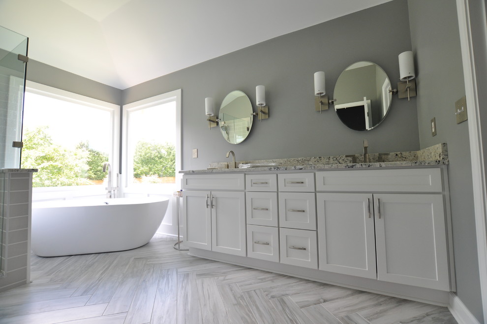 Photo of a medium sized classic ensuite bathroom in Atlanta with shaker cabinets, white cabinets, a freestanding bath, a corner shower, a one-piece toilet, grey tiles, porcelain tiles, grey walls, porcelain flooring, a submerged sink and limestone worktops.