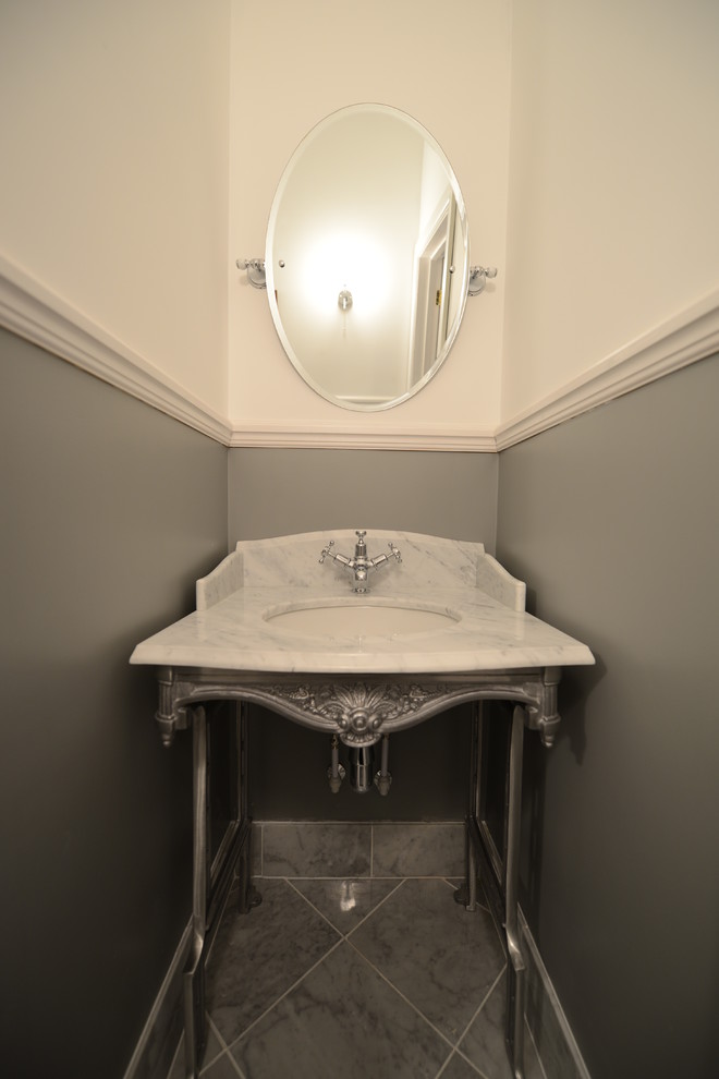 Foto di un bagno di servizio classico di medie dimensioni con lavabo a consolle, top in marmo, WC monopezzo, piastrelle grigie, piastrelle in pietra, pareti grigie e pavimento in marmo