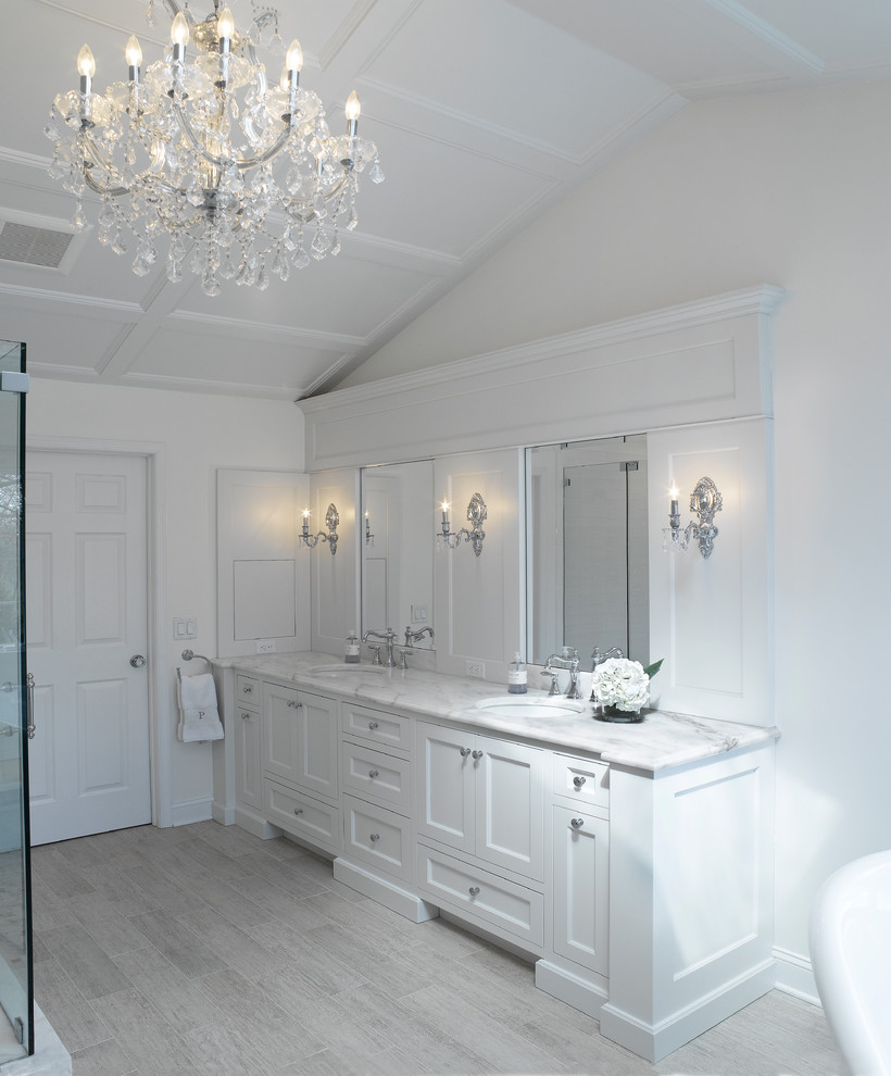 This is an example of a large shabby-chic style ensuite bathroom in New York with a freestanding bath, grey worktops, white walls, porcelain flooring, a submerged sink, grey floors, a hinged door, shaker cabinets, white cabinets, a corner shower and marble worktops.