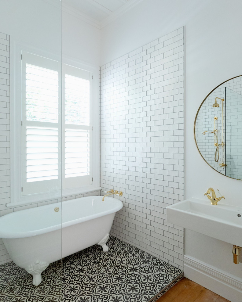 Small traditional ensuite wet room bathroom in Auckland with a claw-foot bath, metro tiles, white walls, ceramic flooring, a trough sink, black floors, an open shower, a single sink and white tiles.