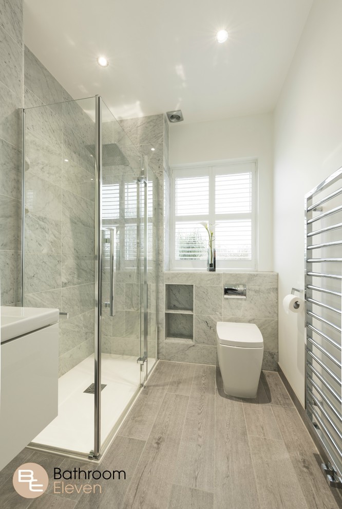 Kleines Modernes Badezimmer mit weißen Schränken, Einbaubadewanne, grauen Fliesen, Steinfliesen, weißer Wandfarbe, Toilette mit Aufsatzspülkasten, offener Dusche, hellem Holzboden und Wandwaschbecken
