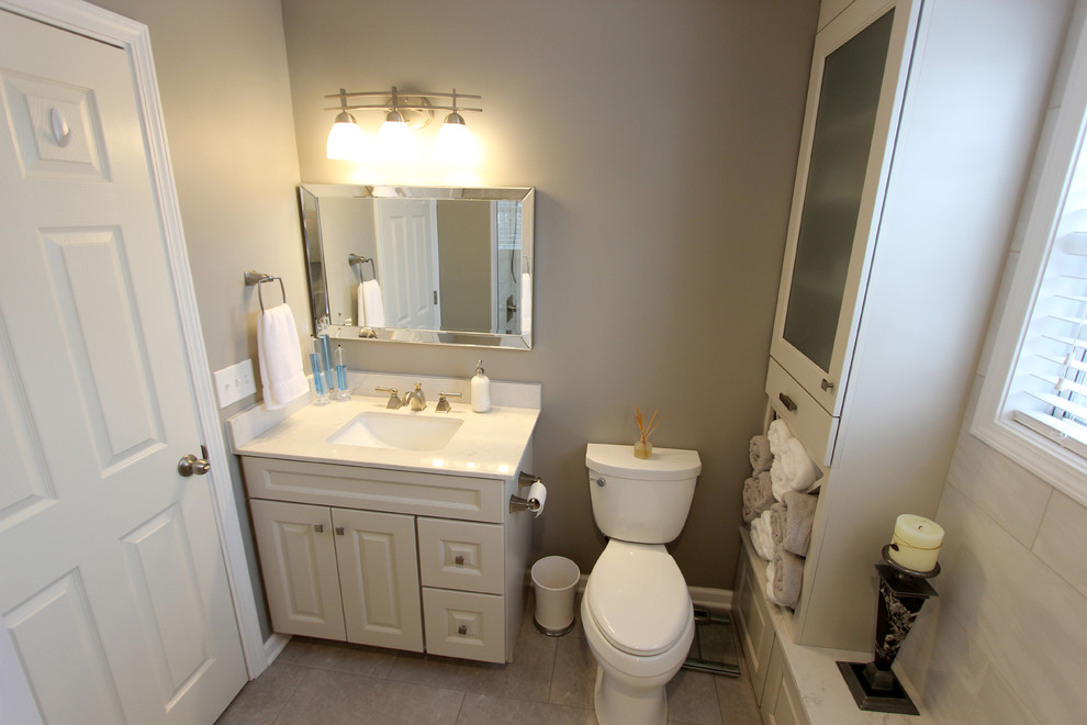 This is an example of a small classic ensuite bathroom in Cleveland with raised-panel cabinets, grey cabinets, an alcove bath, an alcove shower, a two-piece toilet, grey tiles, porcelain tiles, grey walls, porcelain flooring, a submerged sink, solid surface worktops, grey floors and a hinged door.