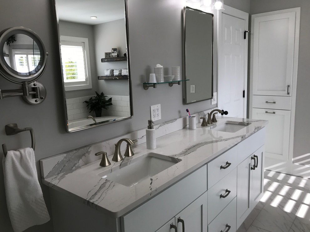 Design ideas for a large classic ensuite bathroom in New York with recessed-panel cabinets, white cabinets, a built-in bath, a corner shower, white tiles, metro tiles, grey walls, marble flooring, a submerged sink, quartz worktops, grey floors and a hinged door.