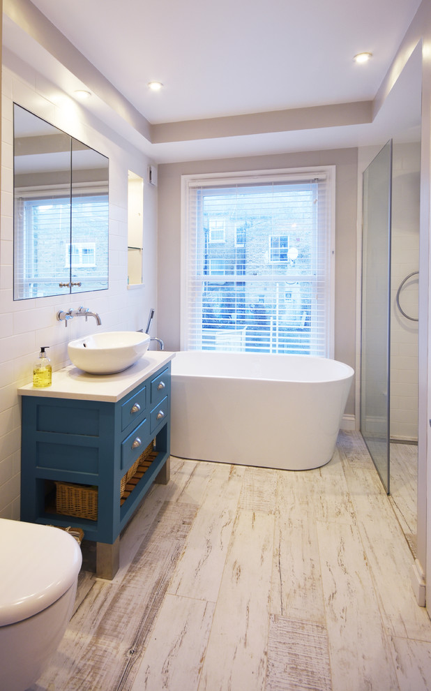 Kleines Modernes Kinderbad mit verzierten Schränken, blauen Schränken, freistehender Badewanne, bodengleicher Dusche, weißen Fliesen, Laminat, weißem Boden und weißer Waschtischplatte in London