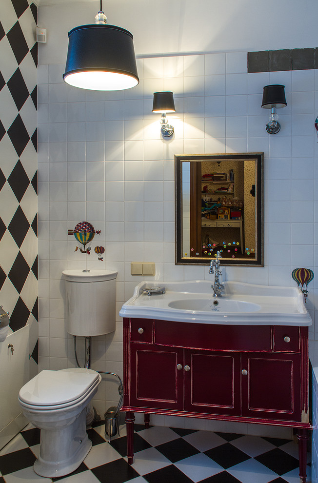 Cette image montre une salle de bain bohème de taille moyenne pour enfant avec des portes de placard rouges, un carrelage blanc, des carreaux de céramique, une baignoire posée, WC à poser, un mur blanc, un sol en carrelage de céramique, un plan vasque et un placard avec porte à panneau encastré.