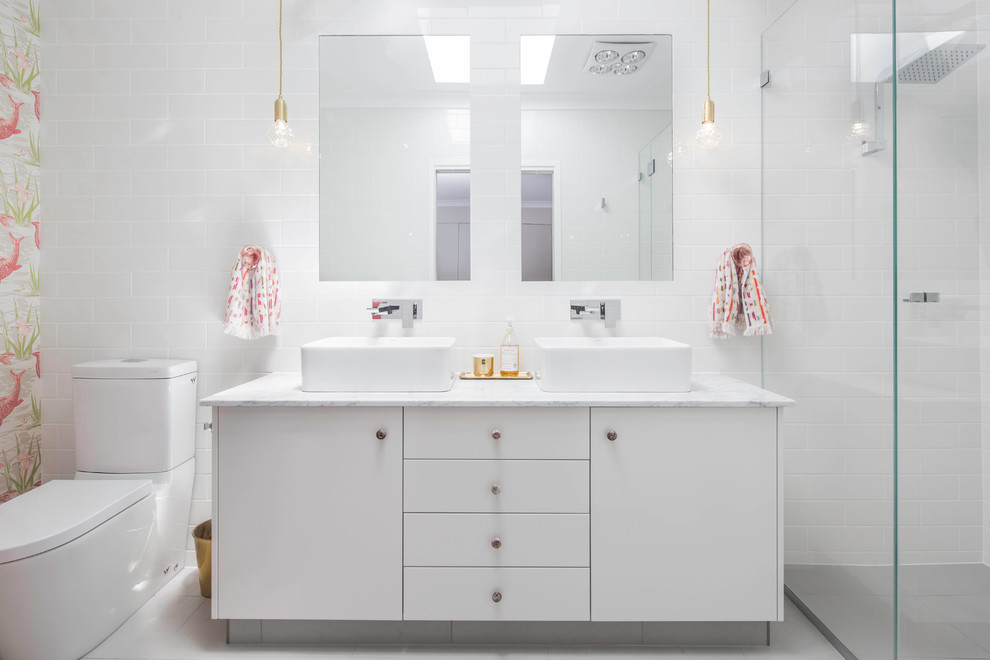 Cette image montre une petite salle de bain principale minimaliste avec un placard en trompe-l'oeil, des portes de placard blanches, une douche double, WC à poser, un carrelage blanc, un carrelage métro, un mur blanc, un sol en carrelage de porcelaine, une vasque, un plan de toilette en marbre, un sol gris et une cabine de douche à porte battante.