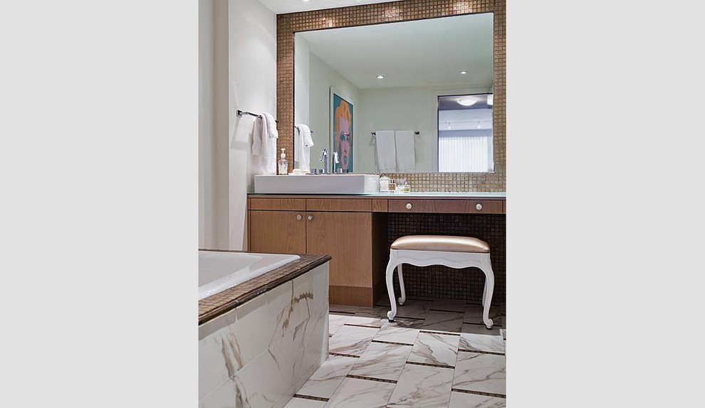 Bild på ett stort funkis en-suite badrum, med ett fristående handfat, släta luckor, skåp i mellenmörkt trä, bänkskiva i glas, ett platsbyggt badkar, brun kakel, glaskakel, beige väggar och klinkergolv i porslin
