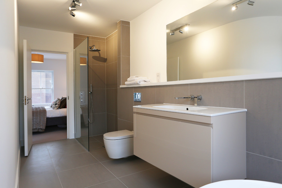 Photo of a large contemporary ensuite bathroom in London with flat-panel cabinets, beige cabinets, a freestanding bath, a walk-in shower, a wall mounted toilet, beige tiles, porcelain tiles, beige walls, porcelain flooring, a wall-mounted sink, engineered stone worktops, beige floors and an open shower.