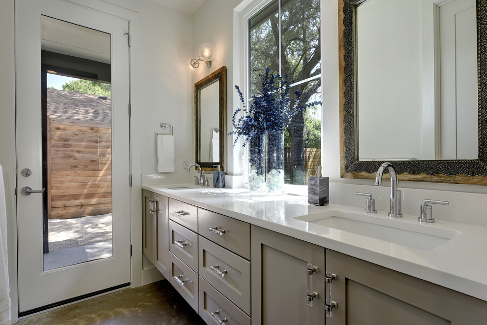 Cette image montre une salle de bain principale minimaliste de taille moyenne avec un placard à porte shaker, des portes de placard grises, un mur blanc, sol en béton ciré et un plan de toilette en surface solide.
