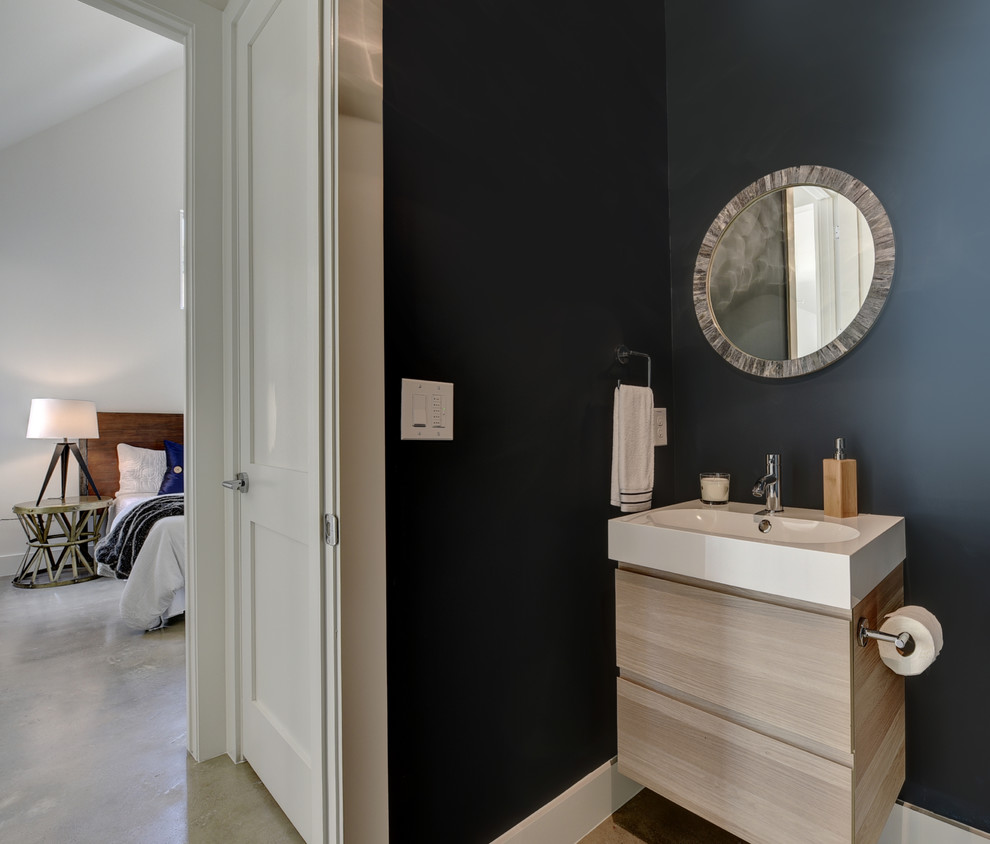 Imagen de cuarto de baño minimalista pequeño con armarios con paneles lisos, puertas de armario de madera clara, paredes azules, suelo de cemento, aseo y ducha, lavabo integrado y encimera de acrílico