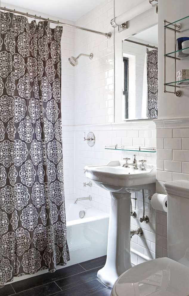 Small traditional bathroom in New York with a pedestal sink, an alcove bath, a shower/bath combination, white tiles, metro tiles, a two-piece toilet, white walls and dark hardwood flooring.