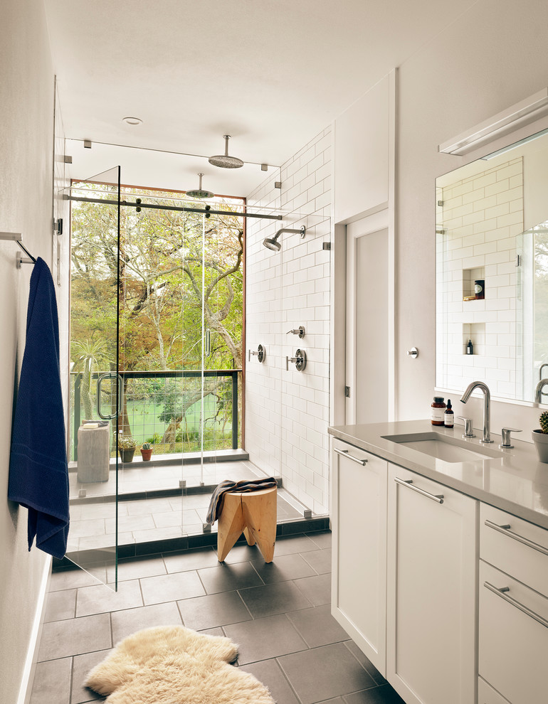 Inredning av ett rustikt grå grått badrum med dusch, med skåp i shakerstil, vita skåp, en dubbeldusch, vit kakel, tunnelbanekakel, vita väggar, ett undermonterad handfat, grått golv och dusch med gångjärnsdörr