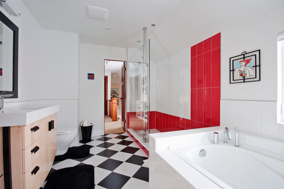 Inredning av ett modernt stort en-suite badrum, med släta luckor, skåp i ljust trä, ett platsbyggt badkar, en öppen dusch, en toalettstol med hel cisternkåpa, svart och vit kakel, porslinskakel, röda väggar, klinkergolv i porslin, ett integrerad handfat, bänkskiva i kvarts, med dusch som är öppen och flerfärgat golv