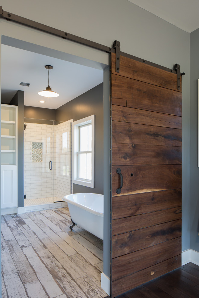 Medium sized country ensuite bathroom in Detroit with a corner shower, a claw-foot bath, a two-piece toilet, white tiles, metro tiles, grey walls, dark hardwood flooring, a wall-mounted sink, brown floors, a hinged door, open cabinets, brown cabinets, wooden worktops and brown worktops.
