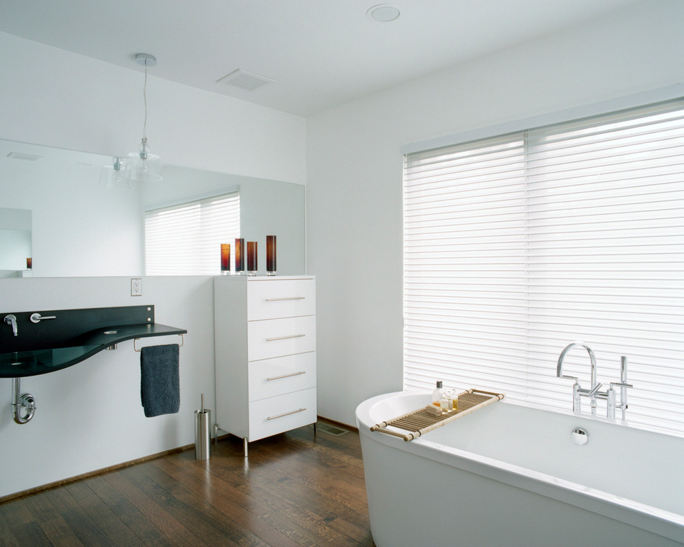 Foto på ett stort funkis en-suite badrum, med släta luckor, vita skåp, ett fristående badkar, vita väggar, mörkt trägolv, ett integrerad handfat och bänkskiva i akrylsten