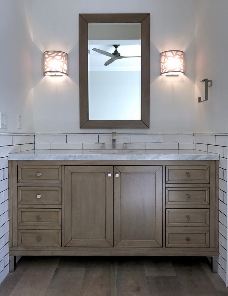 Idée de décoration pour une salle d'eau tradition en bois brun avec un placard en trompe-l'oeil, un carrelage blanc, un carrelage métro, un mur gris, un sol en bois brun, un lavabo encastré et un plan de toilette en marbre.