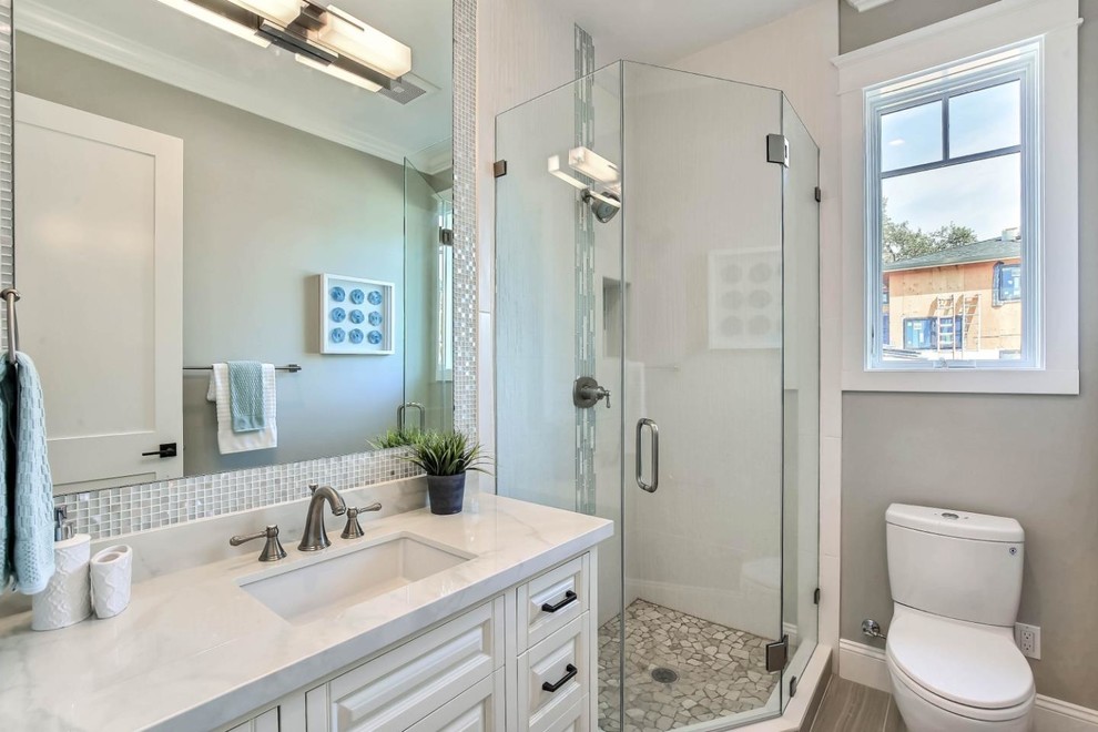 На фото: маленькая ванная комната в стиле кантри с фасадами с выступающей филенкой, белыми фасадами, отдельно стоящей ванной, угловым душем, раздельным унитазом, белой плиткой, керамической плиткой, серыми стенами, полом из керамогранита, душевой кабиной, врезной раковиной, столешницей из искусственного кварца, серым полом и душем с распашными дверями для на участке и в саду