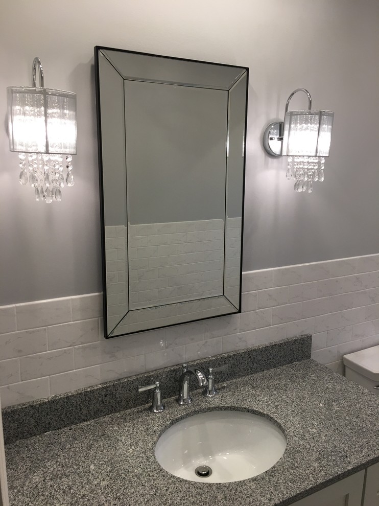 Mid-sized transitional subway tile vinyl floor bathroom photo in New York with recessed-panel cabinets, gray cabinets, a two-piece toilet, gray walls, an undermount sink and granite countertops