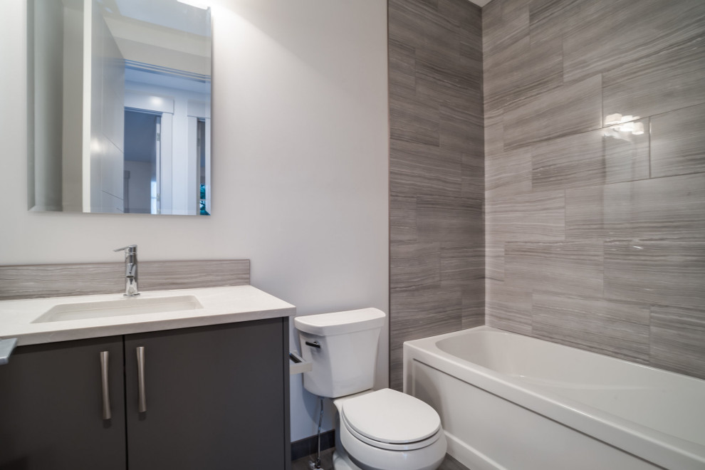 Идея дизайна: ванная комната среднего размера в стиле модернизм с плоскими фасадами, серыми фасадами, отдельно стоящей ванной, душем над ванной, раздельным унитазом, серой плиткой, плиткой кабанчик, белыми стенами, полом из керамической плитки, накладной раковиной, столешницей из искусственного кварца, бежевым полом, шторкой для ванной, разноцветной столешницей, тумбой под две раковины и подвесной тумбой