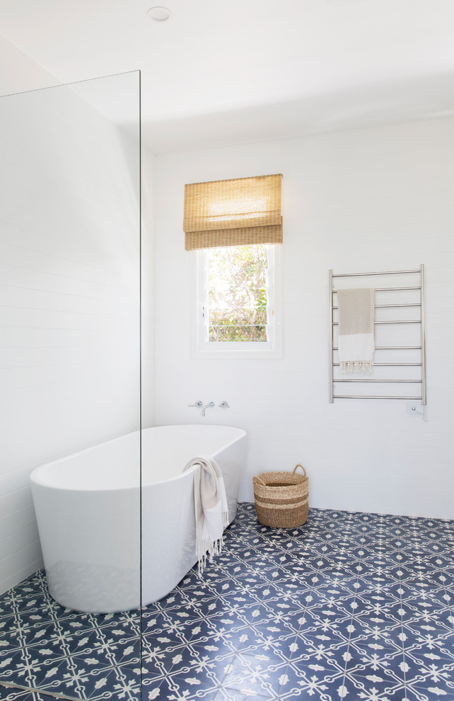 Идея дизайна: большая ванная комната в морском стиле с фасадами в стиле шейкер, белыми фасадами, отдельно стоящей ванной, угловым душем, инсталляцией, серой плиткой, керамогранитной плиткой, белыми стенами, полом из цементной плитки, врезной раковиной, столешницей из искусственного кварца, синим полом, душем с распашными дверями и белой столешницей