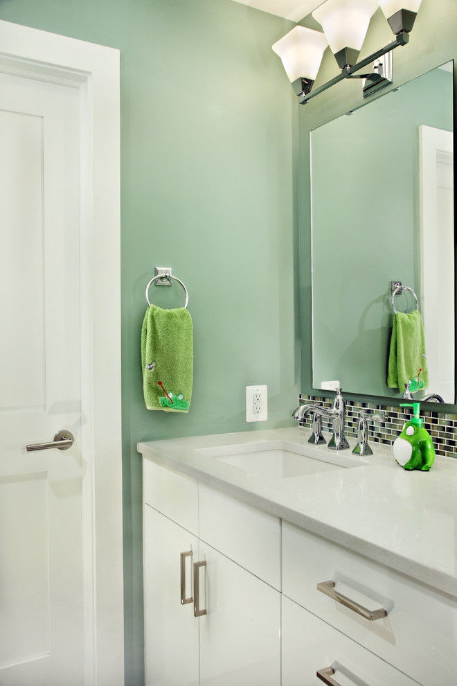 Photo of a small contemporary family bathroom in DC Metro with flat-panel cabinets, white cabinets, a two-piece toilet, blue tiles, grey tiles, green tiles, matchstick tiles, blue walls, a submerged sink and solid surface worktops.