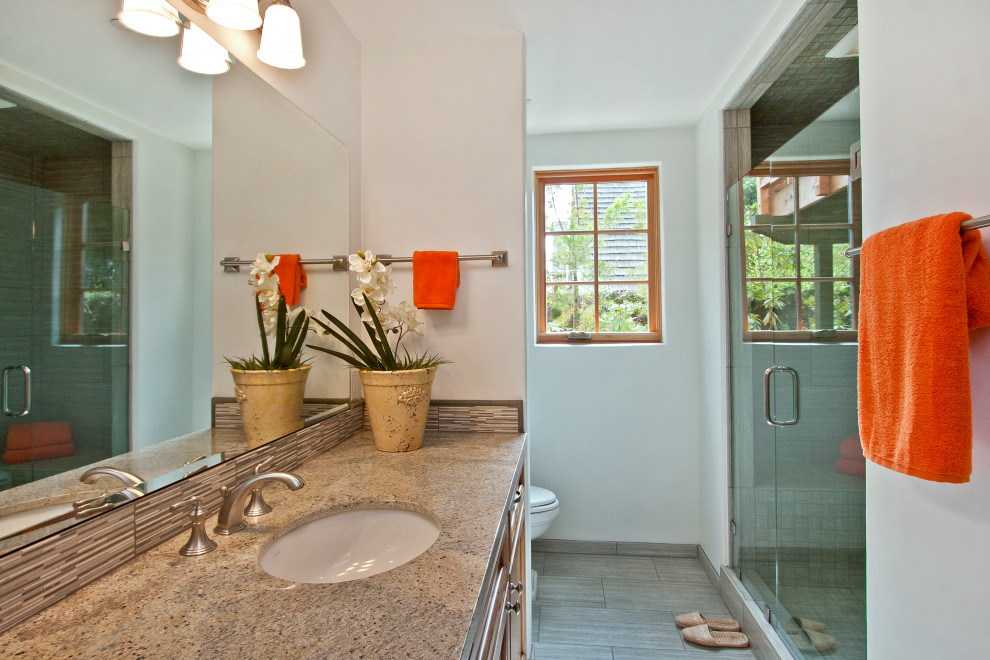Exempel på ett stort klassiskt brun brunt en-suite badrum, med luckor med infälld panel, skåp i mellenmörkt trä, ett platsbyggt badkar, en dusch i en alkov, en toalettstol med separat cisternkåpa, grå kakel, mosaik, vita väggar, klinkergolv i keramik, ett undermonterad handfat, granitbänkskiva, grått golv och med dusch som är öppen