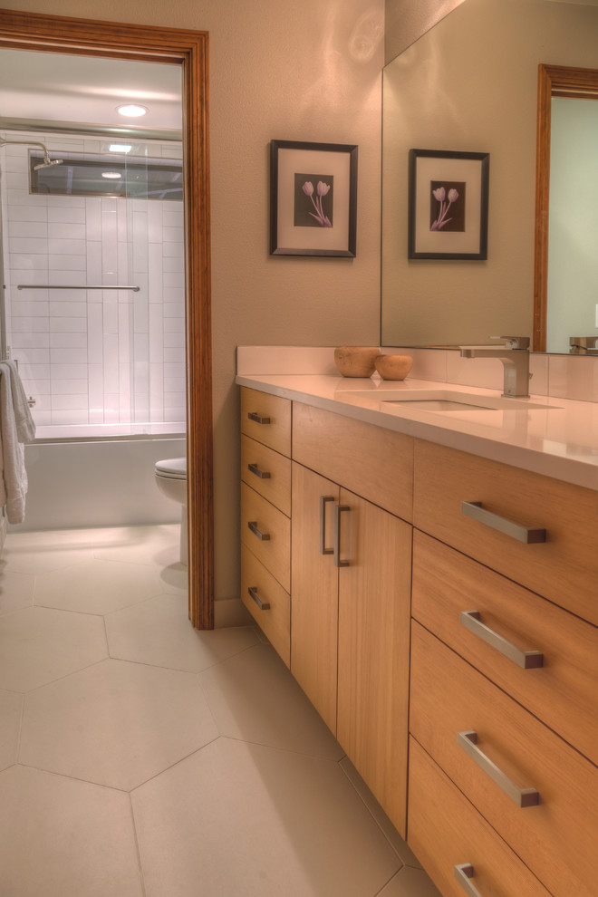 Свежая идея для дизайна: ванная комната среднего размера в стиле модернизм с плоскими фасадами, светлыми деревянными фасадами, душем над ванной, унитазом-моноблоком, бежевой плиткой, керамической плиткой, бежевыми стенами, полом из керамической плитки, монолитной раковиной, столешницей из искусственного камня, белым полом и душем с раздвижными дверями - отличное фото интерьера