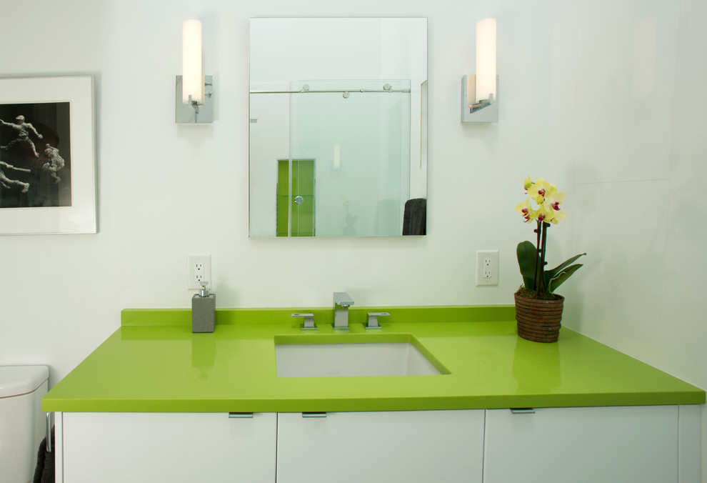 Пример оригинального дизайна: ванная комната среднего размера в стиле модернизм с плоскими фасадами, белыми фасадами, ванной в нише, душем над ванной, раздельным унитазом, серой плиткой, керамогранитной плиткой, белыми стенами, полом из керамогранита, врезной раковиной, столешницей из искусственного камня и зеленой столешницей