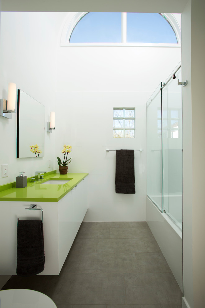 Cette photo montre une salle de bain moderne de taille moyenne avec un placard à porte plane, des portes de placard blanches, une baignoire en alcôve, un combiné douche/baignoire, WC séparés, un carrelage gris, des carreaux de porcelaine, un mur blanc, un sol en carrelage de porcelaine, un lavabo encastré, un plan de toilette en surface solide et un plan de toilette vert.