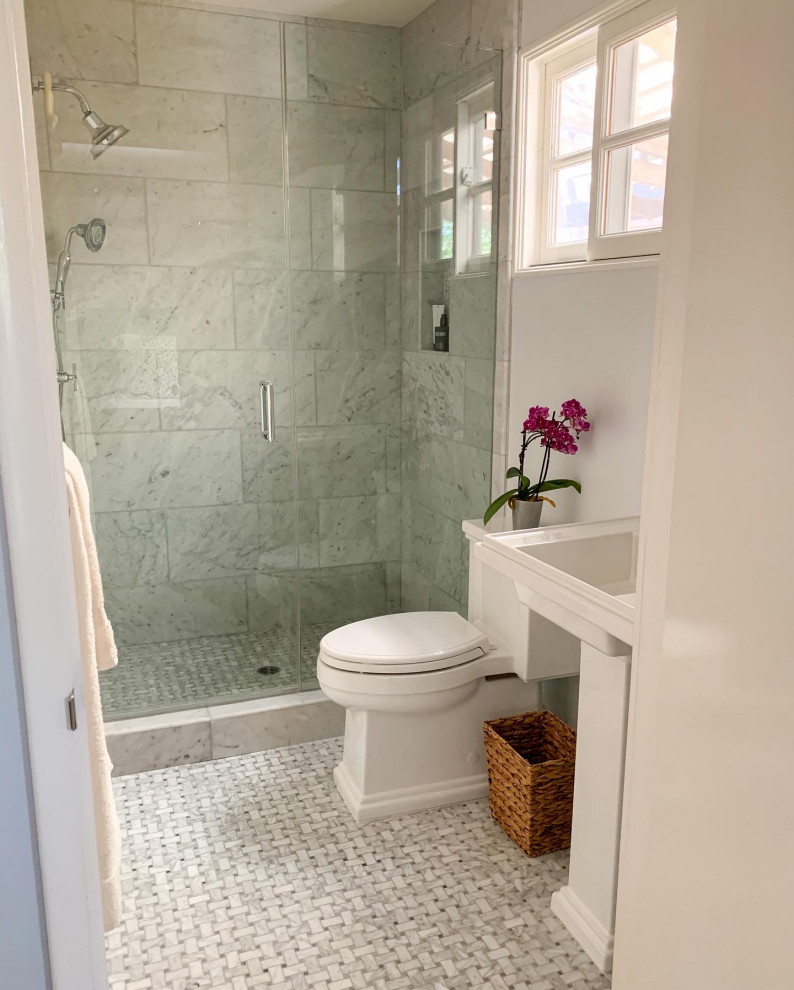 Idéer för att renovera ett litet vintage vit vitt badrum med dusch, med luckor med glaspanel, vita skåp, en dusch i en alkov, en toalettstol med separat cisternkåpa, grå kakel, marmorkakel, blå väggar, marmorgolv, ett piedestal handfat, bänkskiva i akrylsten, grått golv och dusch med gångjärnsdörr