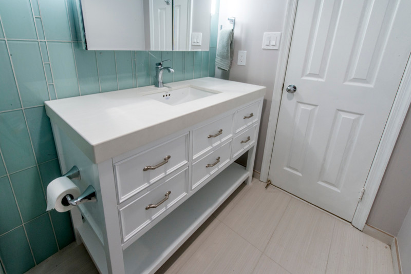 Photo of a medium sized contemporary shower room bathroom in DC Metro with freestanding cabinets, white cabinets, a submerged bath, a shower/bath combination, a two-piece toilet, beige tiles, glass sheet walls, green walls, porcelain flooring, a submerged sink and wooden worktops.