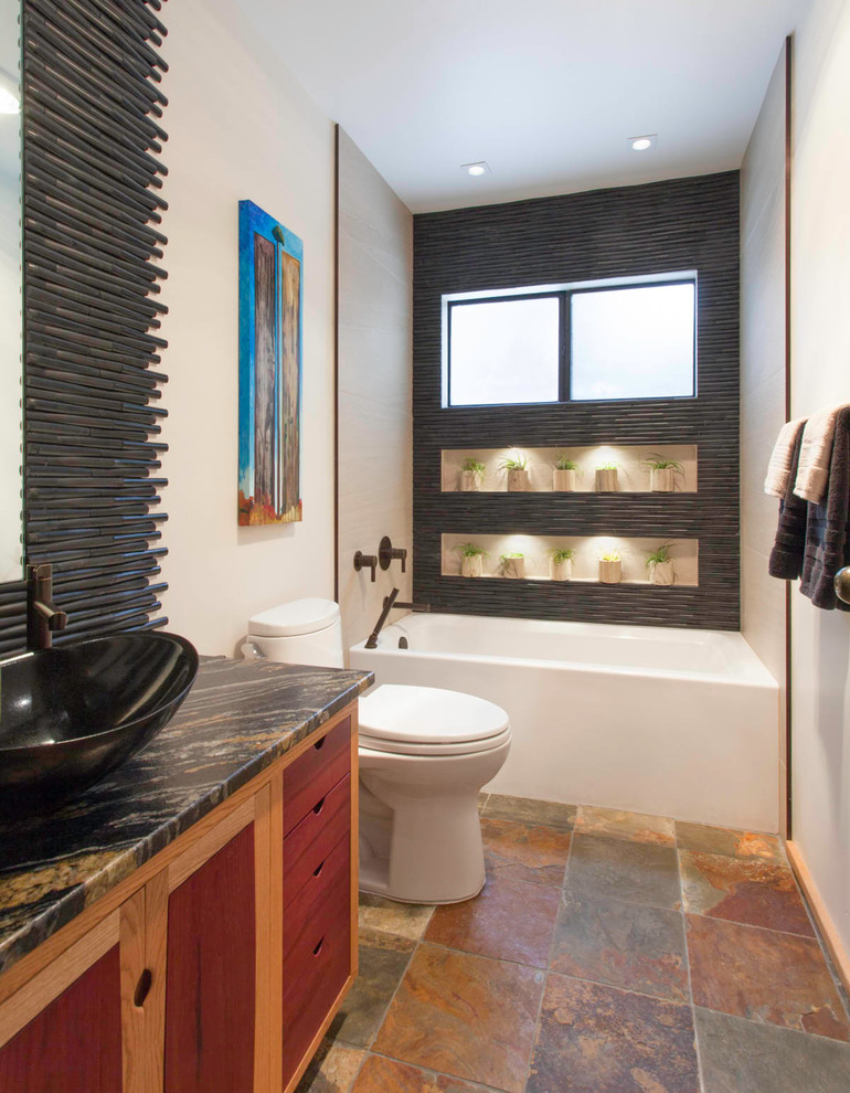Mittelgroßes Retro Badezimmer mit bodengleicher Dusche, Toilette mit Aufsatzspülkasten, schwarzen Fliesen, Schieferboden, Aufsatzwaschbecken, buntem Boden, Falttür-Duschabtrennung und schwarzer Waschtischplatte in San Diego