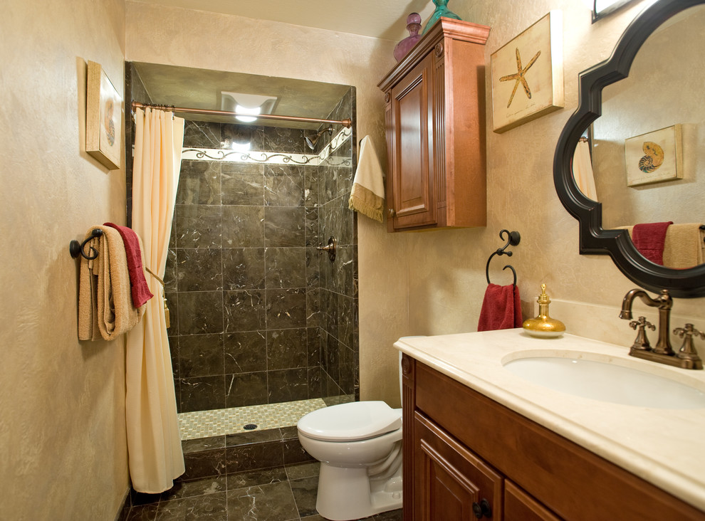 Idée de décoration pour une petite douche en alcôve tradition avec un lavabo encastré, un placard avec porte à panneau surélevé, des portes de placard marrons, un plan de toilette en marbre, WC séparés, un carrelage noir, un carrelage de pierre, un mur beige et un sol en marbre.
