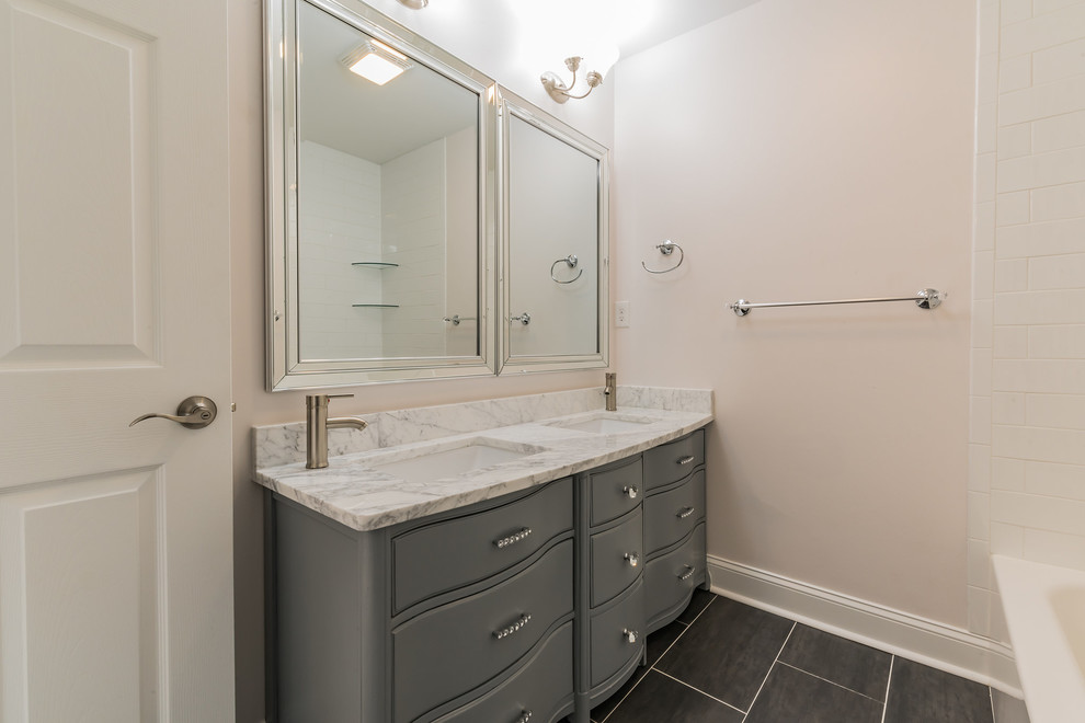 Medium sized traditional ensuite bathroom in Wilmington with freestanding cabinets, grey cabinets, an alcove bath, a shower/bath combination, a two-piece toilet, white tiles, ceramic tiles, white walls, ceramic flooring, a submerged sink, marble worktops, grey floors, a shower curtain, grey worktops, double sinks and a freestanding vanity unit.