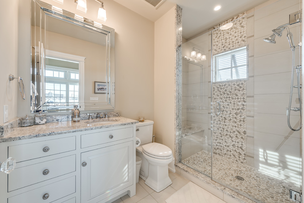 Example of a mid-sized beach style master beige tile and stone tile marble floor bathroom design in Philadelphia with flat-panel cabinets, white cabinets, a two-piece toilet, beige walls and a drop-in sink