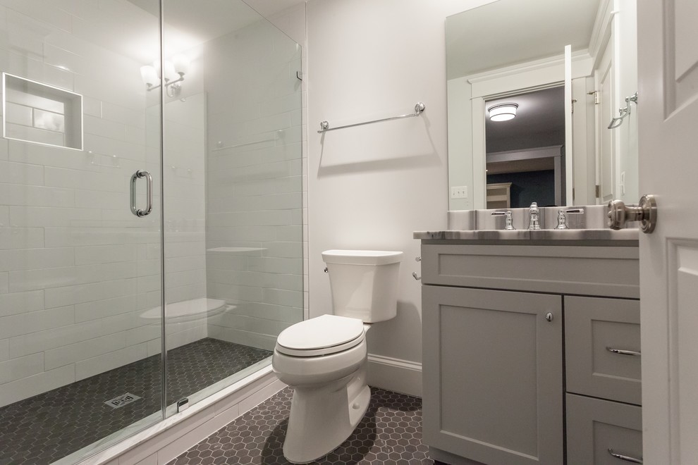 Exempel på ett lantligt grå grått badrum, med skåp i shakerstil, grå skåp, en dusch i en alkov, en toalettstol med separat cisternkåpa, vit kakel, tunnelbanekakel, grå väggar, klinkergolv i porslin, ett undermonterad handfat, bänkskiva i kvartsit, svart golv och dusch med gångjärnsdörr